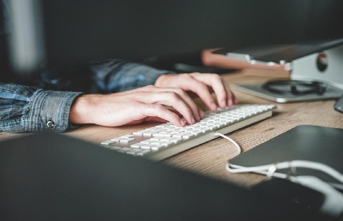 A person typing on a keyboard researching a customer journey orchestration example.